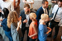 Diverse group at a social event, mingling and networking. People in business attire, engaging in conversation, holding drinks, and smiling in a lively atmosphere. Diverse people talking together.