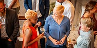 Group of diverse people socializing at a gathering, holding drinks, smiling, in conversation. Social event with diverse individuals enjoying drinks. Diverse people mingle at social gathering.