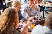 Group of people collaborating at a table, using a laptop. Casual meeting, teamwork, and discussion in a cafe setting. Diverse group, focused on project work. Startup business team working at a cafe.