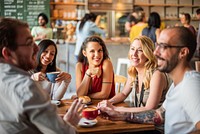 Group of friends enjoying coffee at a cafe. Smiling and chatting. Diverse group in a cozy cafe. Happy diverse friends having a good time in cafe.