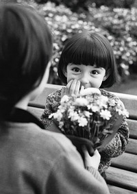 Little boy standing his back to camera and hiding flower bouquet flowers photo bench.