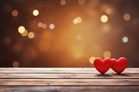 Two red wooden hearts on an old wood table background romantic symbol lights.