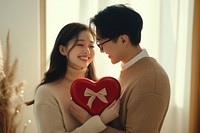 A asian man gives his girlfriend a red heart-shaped box valentine's together couple.