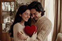 A hispanic america man gives his girlfriend a red heart-shaped chocolate box sweaters together couple.