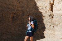 Person hiking in a desert canyon, wearing a hat and backpack. The hiker explores the rocky landscape, enjoying the adventure and natural scenery. Hiking woman outdoor activity photo.