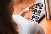 Pregnant woman holding ultrasound images, viewing baby scans. Expectant mother admiring ultrasound photos, anticipating baby's arrival, pregnancy moments. Expectant mother, pregnancy concept.