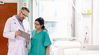 Doctor and nurse discussing patient chart in hospital room. Medical team collaboration. Healthcare professionals in clinical setting. Hospital teamwork. Nurse and doctor discussing in hospital.