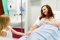 A woman with curly hair lies in a hospital bed, smiling at a young girl. Hospital setting, patient care, and comforting presence are highlighted. Hospital, medical, and healthcare concept.