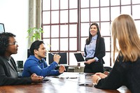 A diverse group in a meeting room. A woman presents with a tablet. Colleagues listen attentively. Business meeting, teamwork, collaboration in modern office. Diverse people business corporate meeting.