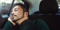 Man sleeping in car, wearing earbuds. Relaxed man resting, peaceful expression. Passenger seat, cozy atmosphere. Man enjoying quiet time, earbuds in ears. A man sleeping and listening music in a car.