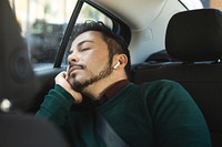 Man sleeping in car, wearing earbuds. Relaxed man, peaceful expression. Passenger seat, man resting. Casual attire, serene atmosphere, man dozing off.  A man sleeping and listening music in a car.