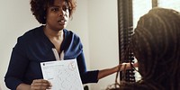 A woman shows a graded paper with an 'F' to another person. The woman appears concerned, discussing the failing grade. The focus is on the paper and the woman's expression. Educational concept.