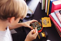 Young boy working on a small robot, using tools to assemble electronic parts. Focused on robotics, electronics, and engineering. Learning and building with robotics. Young boy and hobby.