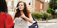 Woman with curly hair talking on phone, calling car insurance, standing on street. Expressive conversation, urban setting. Engaged in phone call, outdoor scene. Car accident concept photo.