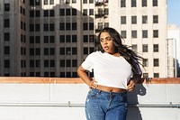 Woman in casual outfit on rooftop. Urban setting with city buildings. Casual fashion, relaxed pose. Cityscape, casual style, rooftop view. Woman in simple white T-shirt photo for mockup.