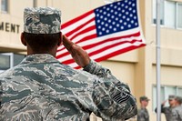 U.S. Air Force Tech. Sgt. Joe Gamble, foreground, a professional military education instructor with the 374th Force Support Squadron Airman Leadership School, salutes as a U.S. flag is lowered during a retreat ceremony at Yokota Air Base, Japan, Sept. 26, 2013.