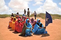 A young woman holds the Somali flag during a demonstration by a local militia, formed to provide security in Marka, Somalia, on April 30. AU UN IST PHOTO / Tobin Jones. Original public domain image from Flickr