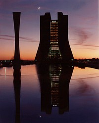 Night, in the form of a crescent moon, overtakes the fading light of day beyond Wilson hall at Fermi National Accelerator Laboratory. Original public domain image from Flickr