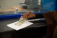 A customer receives one hundred dollars from a bank cashier during the opening ceremony of Premier Bank in Mogadishu, Somalia. Original public domain image from Flickr