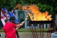 Sgt. Maj. of the Marine Corps Ronald Green, back, and Marine Cpl. Ray Hennagir, center, light the torch for the 2015 Department of Defense Warrior Games Opening Ceremony at the National Museum of the U.S. Marine Corps in Triangle, Va. June 19, 2015. Original public domain image from Flickr