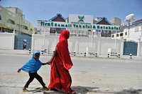 A mother and her daughter, walk past the offices of the first insurance company in Somalia called 'Takaful & Retakaful,' (meaning Insurance & Re-Insurance) in Mogadishu, Somalia on July 26, 2015. AMISOM Photo / Omar Abdisalam. Original public domain image from Flickr