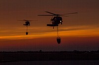A pair of California National Guard UH-60 Black Hawk helicopters from B Company, 1st Battalion, 140th Aviation Regiment, return at sunset to Camarillo Airport in Camarillo, California, Sun., Dec. 10, 2017, after making their last water drops of the day on the Thomas Fire burning in Ventura County.