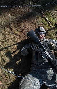 U.S. Army Sergeant Hunter Porter, a Health Care Specialist, maneuvers underneath barbed wire during the training portion of the U.S. Army Europe Expert Field Medical Badge (EFMB) qualification test at Baumholder, Germany on Mar. 17, 2016.