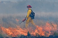 U.S. Air Force Staff Sgt. Daniel Easterlund, a fire protection specialist assigned to the 673rd Civil Engineer Squadron, uses a drip torch to light a back fire during a controlled burn at Grezelka range on Joint Base Elmendorf-Richardson, Alaska, May 2, 2016. According to the National Oceanic and Atmospheric Administration, last winter in Alaska was the second warmest on record dating back to 1925. Combined with record-low snowfall and precipitation, the chance of fire activity greatly increases as combustible dry detritus accumulates. Controlled burns reduce the chance of spot fires by removing excess dry brush and grass. (U.S. Air Force photo/Alejandro Pena). Original public domain image from Flickr