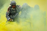 Army Pfc. Tim Hofmann, a native of Atwater, Minn., left, and Spc. Alex Sidoa, a native of Houston, Texas, help Army Sgt. Michael Barnes, a native of Minneapolis, Minn., through the smoke marking a simulated casualty extraction point during a Situation Exercise Training lane during the Ready Warrior Competition at Camp Madbull on Joint Base Elmendorf-Richardson, Alaska, Thursday, June 23, 2016. The three-day competition tested teams of Soldiers assigned to U.S. Army Alaska’s 17th Combat Sustainment Support Battalion in physical fitness, small arms proficiency, land navigation, and small-unit tactics as well as other Soldier skills. (U.S. Air Force photo/Justin Connaher). Original public domain image from Flickr