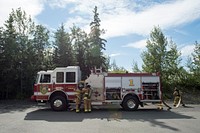 U.S. Air Force fire protection specialists assigned to the 673d Civil Engineer Squadron, unload fire hoses while responding to a simulated structure fire during wartime-firefighting readiness training at Joint Base Elmendorf-Richardson, Alaska, Aug. 24, 2018. During the readiness training the Air Force firefighters donned various levels of mission oriented protective posture (MOPP) gear and practiced responding to emergency situations in a simulated toxic environment during a chemical, biological, radiological, or nuclear strike. (U.S. Air Force photo by Alejandro Peña). Original public domain image from Flickr