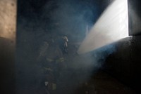 A U.S. Air Force fire protection specialist assigned to the 673d Civil Engineer Squadron, ventilates a smoke-filled room while battling a simulated structure fire during wartime-firefighting readiness training at Joint Base Elmendorf-Richardson, Alaska, Aug. 23, 2018. During the readiness training the Air Force firefighters donned various levels of mission oriented protective posture (MOPP) gear and practiced responding to emergency situations in a simulated toxic environment during a chemical, biological, radiological, or nuclear strike. (U.S. Air Force photo by Alejandro Peña). Original public domain image from Flickr