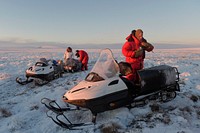 U.S. Marine Corps 1st Sgt. Joshua Guffey, right, Capt. Michael Sickels, center, and local guide Dickie Moto, pause to momentarily rest and adjust their gear while traveling via snow machine from Deering to Kotzebue, Alaska, Dec. 1, 2016. Guffey and Sickels, assigned to Detachment Delta, 4th Law Enforcement Battalion, traveled in sub-zero temperatures to multiple villages in the Northwest Arctic Borough to deliver holiday presents to Alaskan children as part of Toys for Tots. Toys for Tots is supported by the United States Marine Corps Reserve with a goal of delivering, through a new toy during the holiday season, a message of hope to youngsters that will assist them in becoming responsible, productive and patriotic citizens. (U.S. Air Force photo/Alejandro Pena). Original public domain image from Flickr