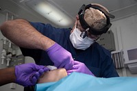 180918-N-IG466-0300 ATLANTIC OCEAN (Sept. 20, 2018) Lt. Cmdr. Wilfredo Palau, right, performs dental surgery on a patient in the dental lab aboard the Nimitz-class aircraft carrier USS Harry S. Truman (CVN 75).