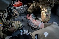 U.S. Army Sgt. Deven Scelfo, left, a flight medic, and Spc. Gabriel Thibault, a UH-60L Black Hawk crew chief treat a simulated casualty with an intravenous line during medical evacuation training on Nov. 14, 2018.