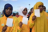 Somalia ladies hold white cards as symbols of peace, at a ceremony to mark International Sports Day for development and peace in Mogadishu on April 06, 2017. UN Photo / Ilyas Ahmed. Original public domain image from Flickr