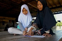 Membaca Bersama Ibu. Aisyah mengajar ibunya belajar membaca buku cerita. Photo by USAID Indonesia. Original public domain image from Flickr