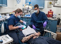 MEDITERRANEAN SEA (June 19, 2017) Lt. Caitlyn Hoysock, left, and Hospital Corpsman 3rd Class Aaron Munzlinger perform a root canal operation on a Sailor in the dental office aboard the aircraft carrier USS George H.W. Bush (CVN 77) (GHWB).