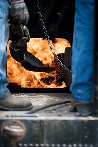 Charcoal is shoveled into the furnace of a steam driven tractor that powers a belt powered antique threshing machine in the 1900 era village at the Iowa Living History Farms, Urbandale, IA, on Aug. 5, 2017.