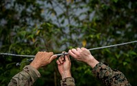 U.S. Army Maj. Robert Vandertuin, left, and U.S. Marine Maj. Jeremy Carroll fix a wire on a fence that helps mitigate elephant stampedes of up to 40 elephants in the area in Chachoengsao, Kingdom of Thailand, Jan. 31, 2018.