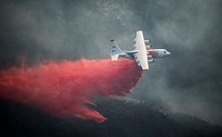 A Coulson C-130 sprays fire retardant ahead of the leading edge of the Thomas Fire, Dec. 13, 2017. The 146th Airlift Wing and civilian companies were activated to support CAL FIRE with wildfire suppression efforts within the state. Original public domain image from Flickr