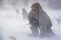 U.S. Air Force Staff Sgt. Benjamin Reynolds, a response force leader assigned to the 891st Missile Security Forces Squadron, crouches in rotor wash in the Turtle Mountain State Forest, North Dakota, Feb. 14, 2018, during a field training exercise.
