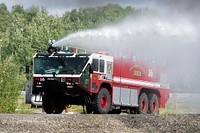 U.S. Air Force fire protection specialists assigned to the 673d Civil Engineer Squadron, spray water from their Striker aircraft rescue and firefighting vehicle while responding to a simulated aircraft fire during wartime-firefighting readiness training at Joint Base Elmendorf-Richardson, Alaska, Aug. 24, 2018. During the readiness training the Air Force firefighters donned various levels of mission oriented protective posture (MOPP) gear and practiced responding to emergency situations in a simulated toxic environment during a chemical, biological, radiological, or nuclear strike. (U.S. Air Force photo by Alejandro Peña). Original public domain image from Flickr