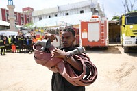 A member of the Mogadishu's Fire and Emergency Response Service serving under the Benadir Regional Administration holds a hose during a routine morning drill in Mogadishu, Somalia, on 26 May 2018. UN Photo / Omar Abdisalan. Original public domain image from Flickr