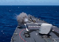 The Arleigh Burke-class guided-missile destroyer USS Curtis Wilbur (DDG 54) fires a mark 45 five-inch gun from the forecastle during a live-fire training while operating in the Philippine Sea, March 10, 2019.