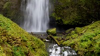 A tourist takes a picture in front of Multnomah Falls, Columbia River Gorge, Oregon. Original public domain image from Flickr