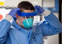 200330-N-PH222-1063 LOS ANGELES (March 30, 2020) Hospital Corpsman 3rd Class Erick Galindo, from El Paso, Texas, dons a splash shield in the micro laboratory aboard the hospital ship USNS Mercy (T-AH 19) March 30.