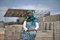 Naema Adam, who began a brick-making business, sits in front of her factory in the Somali capital, Mogadishu on 20 January 2014. AU-UN IST Photo / Tobin Jones. Original public domain image from <a href="https://www.flickr.com/photos/au_unistphotostream/50481277168/" target="_blank" rel="noopener noreferrer nofollow">Flickr</a>