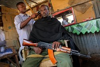 A fighter of the pro-government Ras Kamboni militia gets a haircut inside a barber's kiosk in a market area in the centre of the southern Somali port city of Kismayo, approx.
