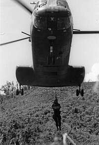 Med Evac - A Marine hangs from a hoist of a Sea Knight helicopter during operations supporting Lancaster II near the Demilitarized Zone. The intense heat, steep hills, and thick undergrowth took their toll in Marine heat casualties which were evacuated for medical attention.