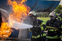 New Jersey state fire protection specialists Ashley Gilliam, left, and Fire Capt. Joe Tomasella with the New Jersey Air National Guard's 177th Fighter Wing extinguish a simulated aircraft engine fire during live fire training at the Aircraft Rescue and Fire Fighting Training Center, Philadelphia International Airport, Pa., Sept. 15, 2020. The Atlantic City Air National Guard Base firefighters perform aircraft live fire training twice a year. The state-of-the-art facility is equipped with a simulator, which allows for interior and exterior training and includes a multitude of various fire scenarios, and an aircraft mock-up inside a propane fed pit. (New Jersey National Guard photo by Mark C. Olsen). Original public domain image from Flickr